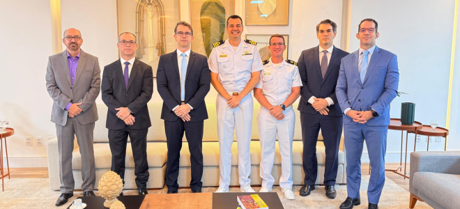 Imagem Representantes da JFPB e da Marinha estão em pé, em uma sala clara, posando para a foto. Ao fundo, há quadros decorativos e uma parede em tom claro. No centro, o comandante da Capitania dos Portos da Paraíba sorri, ladeado por magistrados e representantes da Justiça Federal na Paraíba.