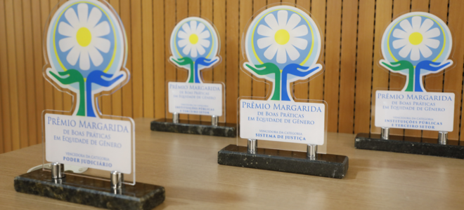 Imagem Foto mostrando 4 prêmios margaridas sobre uma mesa de madeira.